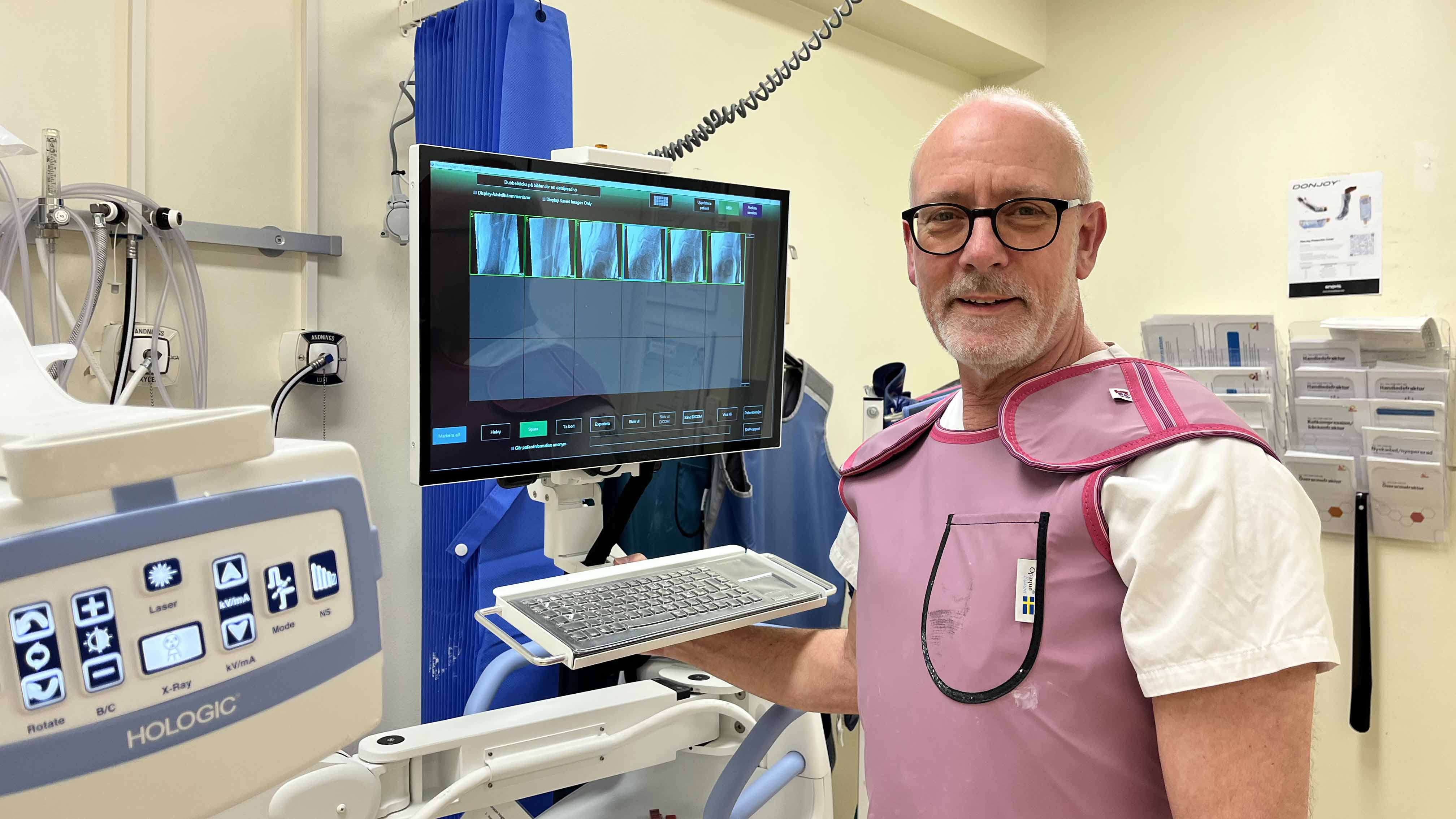 Tommy Åkesson, iförd förkläde, står framför en skärm med röntgenbilder