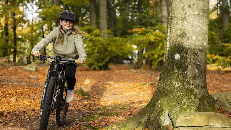 Flicka på cykel i skogen