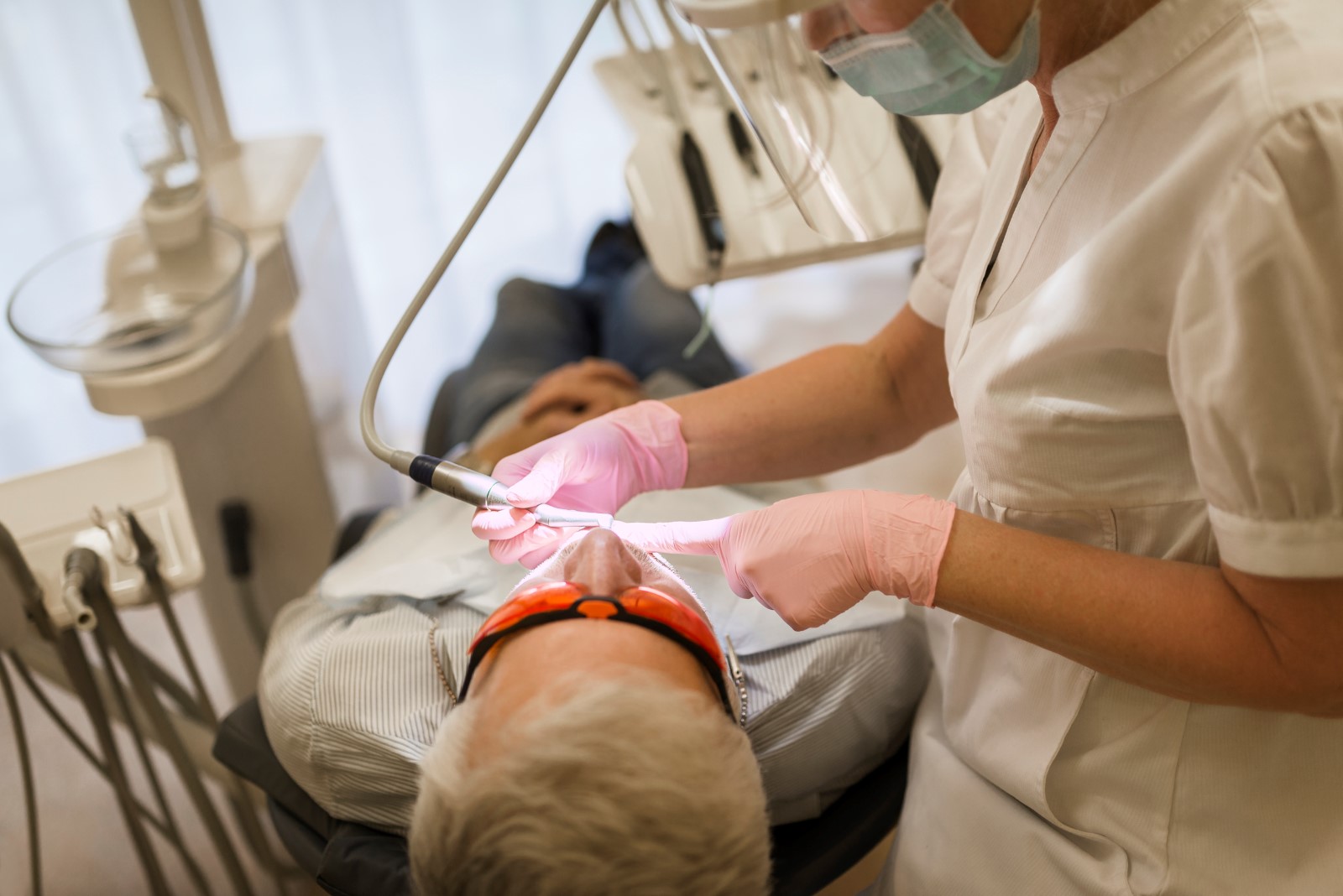 En tandläkare behandlar en patient som ligger på en behandlingsstol.