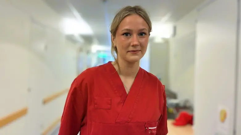 Henrietta Schale i röda jobbkläder i sjukhuskorridor