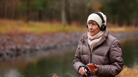 Kvinna lyssnar på podd utomhus.