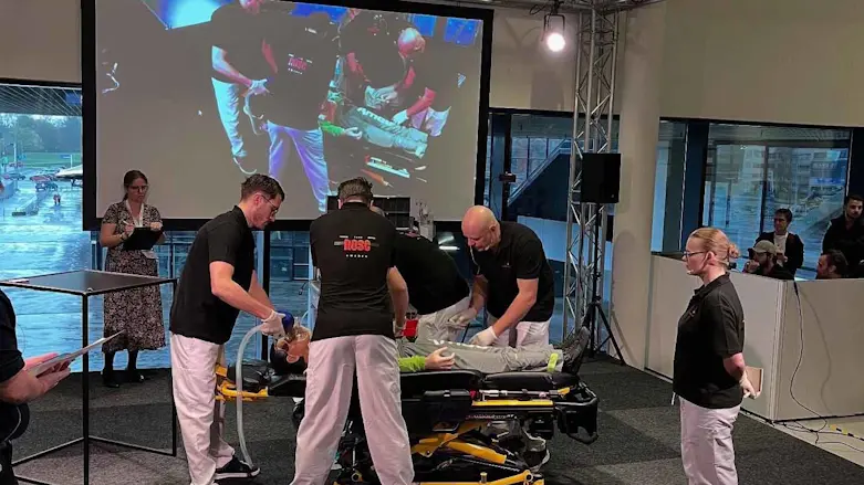 Tävlande står runt bår och och gör HLR på en docka