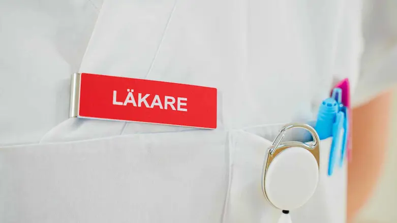 Närbild på sjukhusklädd person med röd bricka med ordet Läkare
