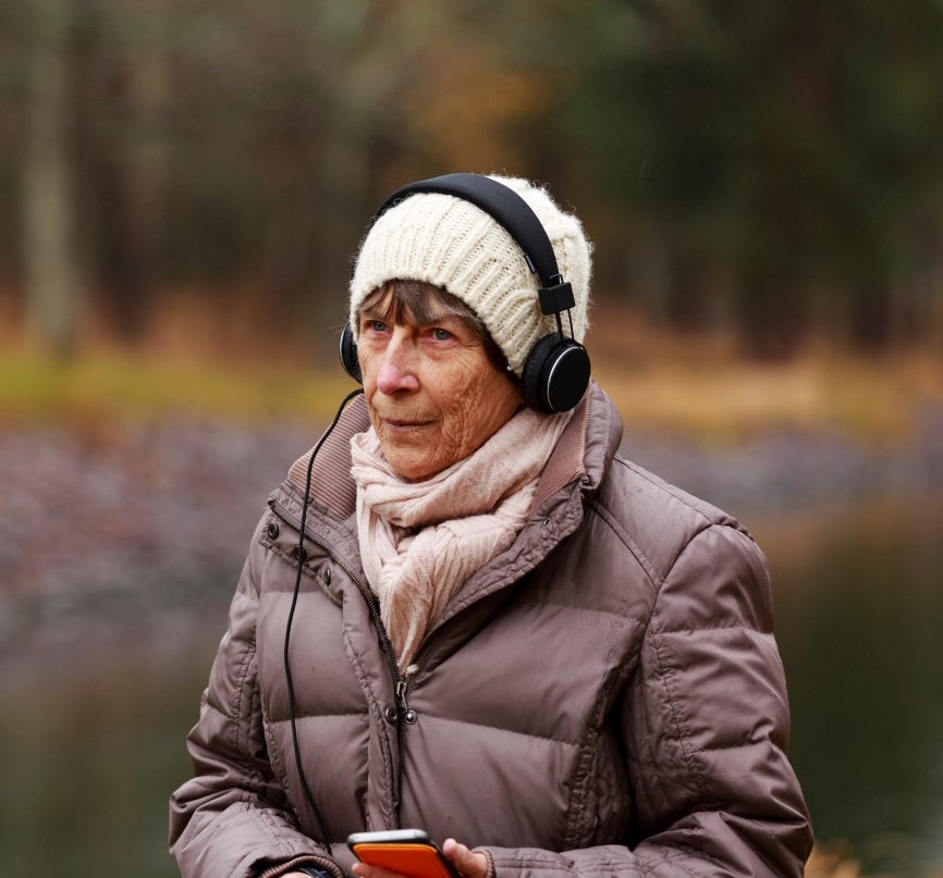 Äldre kvinna med hörlurar.