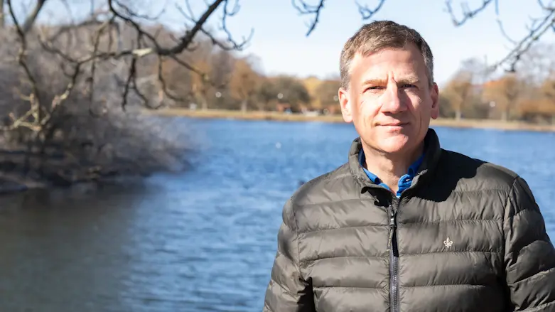 Olle Melander står i jacka framför Pildammarna i Malmö och tittar in i kameran.