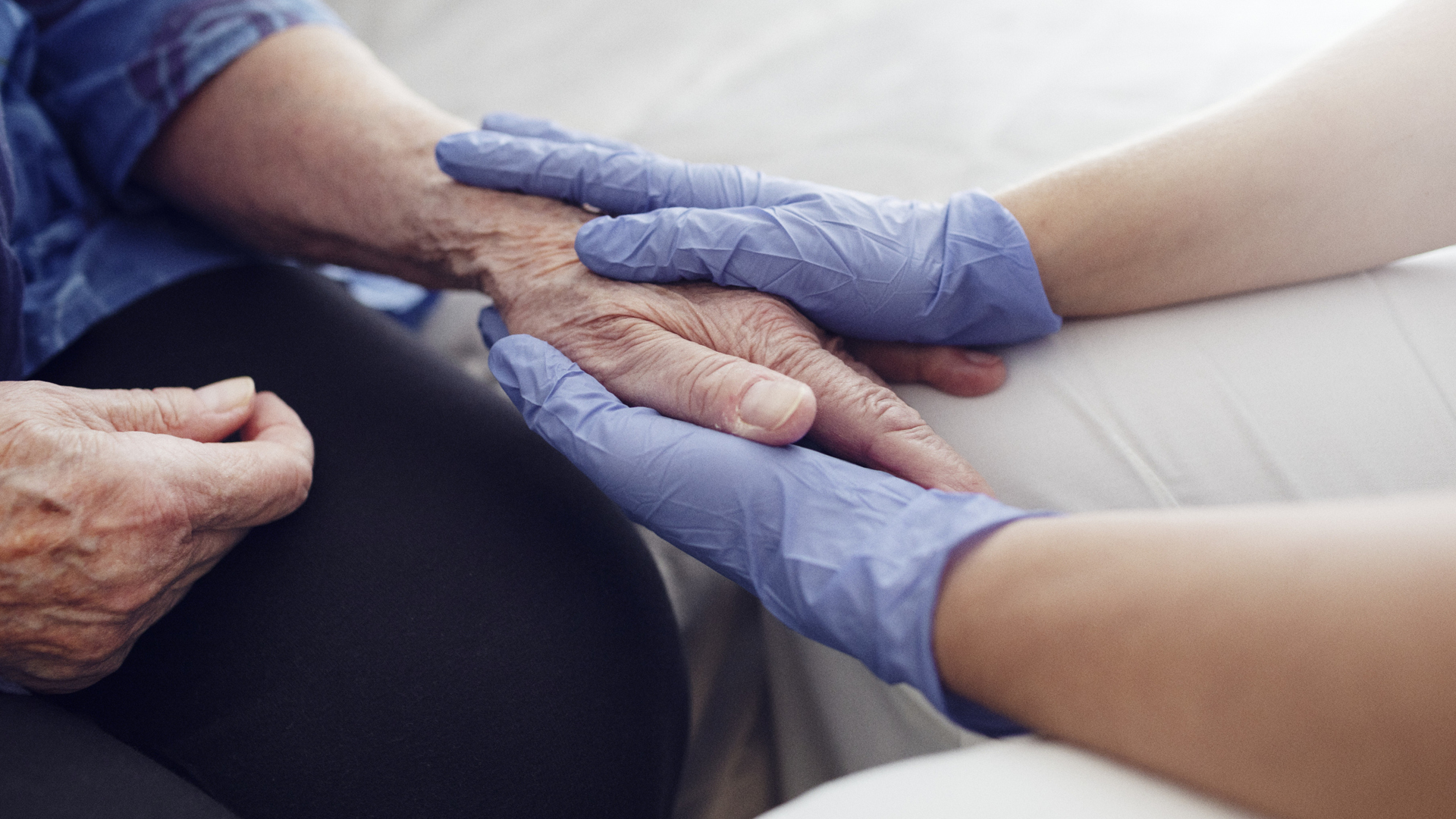 Vårdanställds hand och händer på en äldre person. 