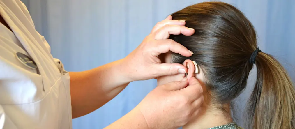 En kvinna får en hörapparat utprovad.