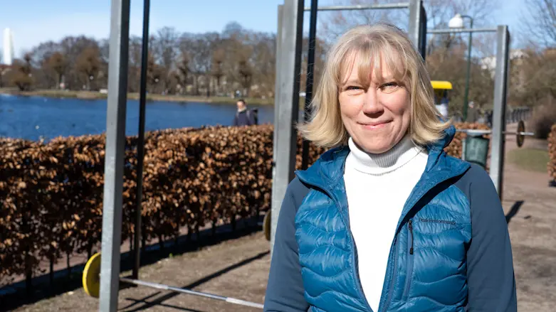 En kvinna står utomhus vid ett utegym och tittar in i kameran.