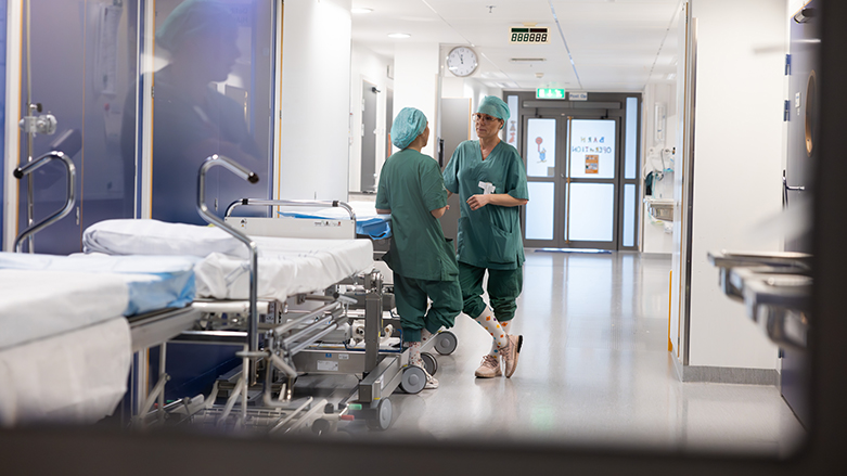 Två vårdmedarbetare samtalar med varandra i en sjukhuskorridor.