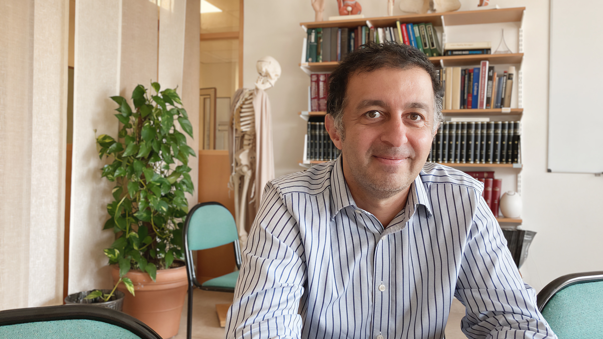 En medelålders man med mörkt hår , klädd i skjorta tittar in i kameran.