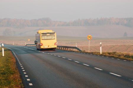 Gul regionbuss kör på landsväg.