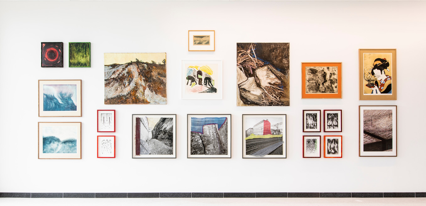 vit vägg inomhus med upphängda tavlor i flera olika storlekar