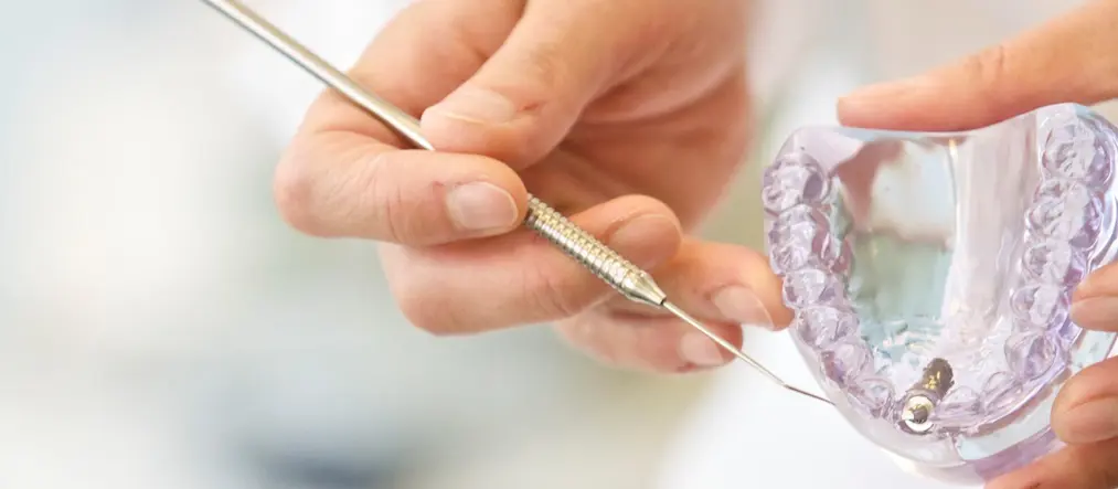 Händer håller i en skena för tänder.