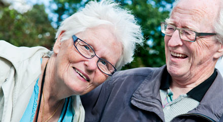 Äldre par ler mot kameran