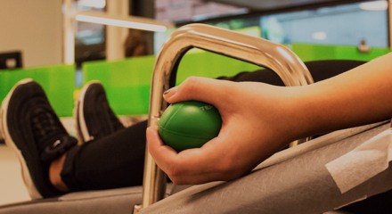 Hand som kramar en grön stressboll under blodgivning. 