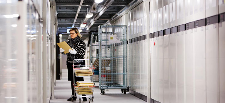 Kvinna står vid lång rad arkivskåp. Foto: Christiaan Dirksen