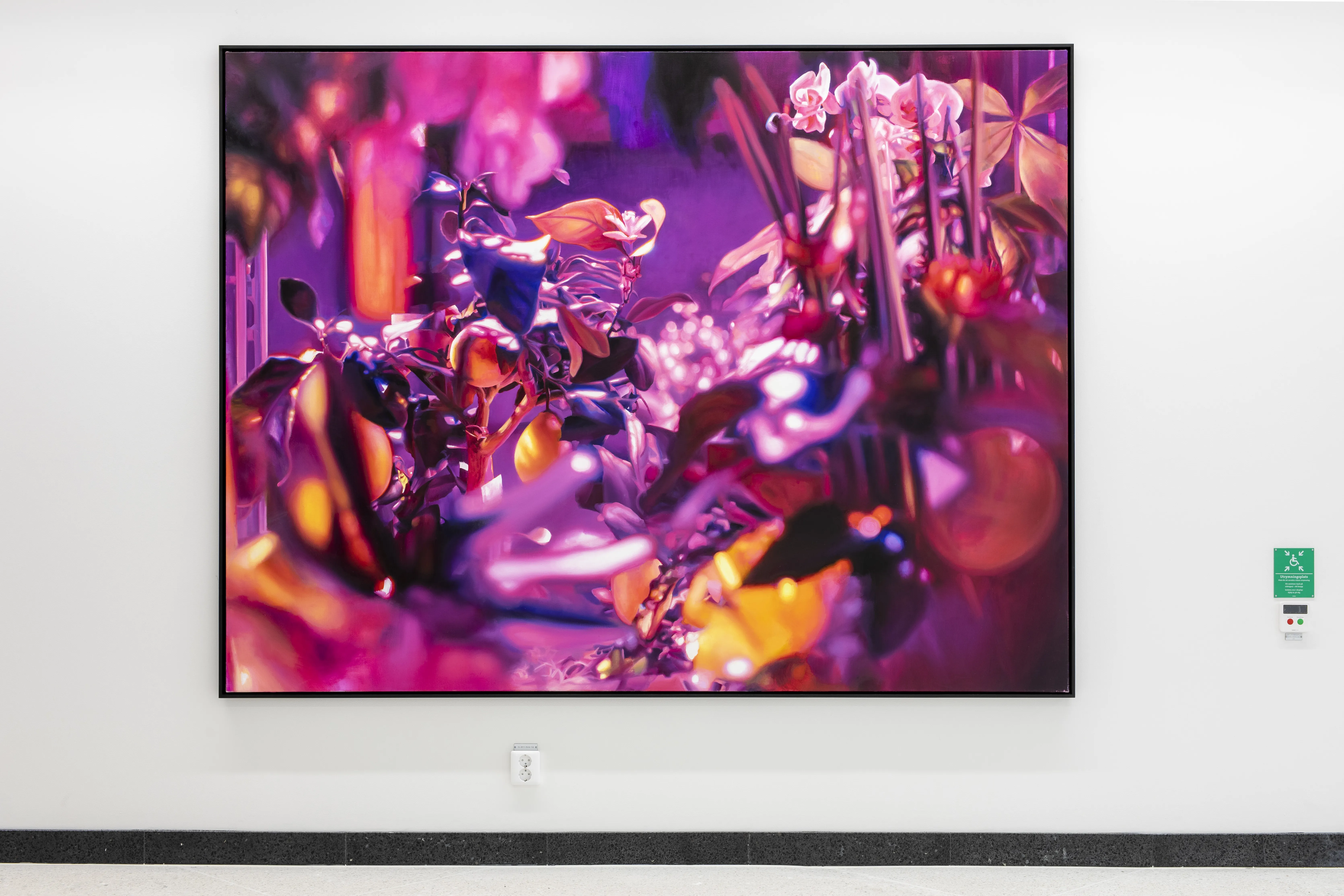 En målning i rosa och lila färg hänger på en vit vägg. Målningens motiv är ett utsnitt av en krukväxt.