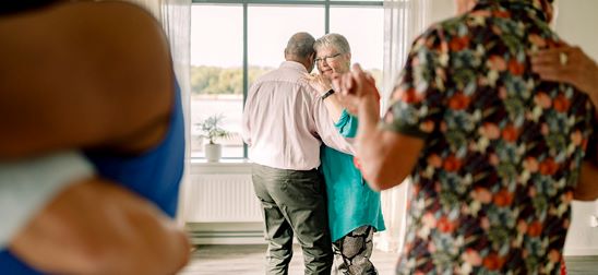 Äldre par dansar tillsammans i ett ljust rum.