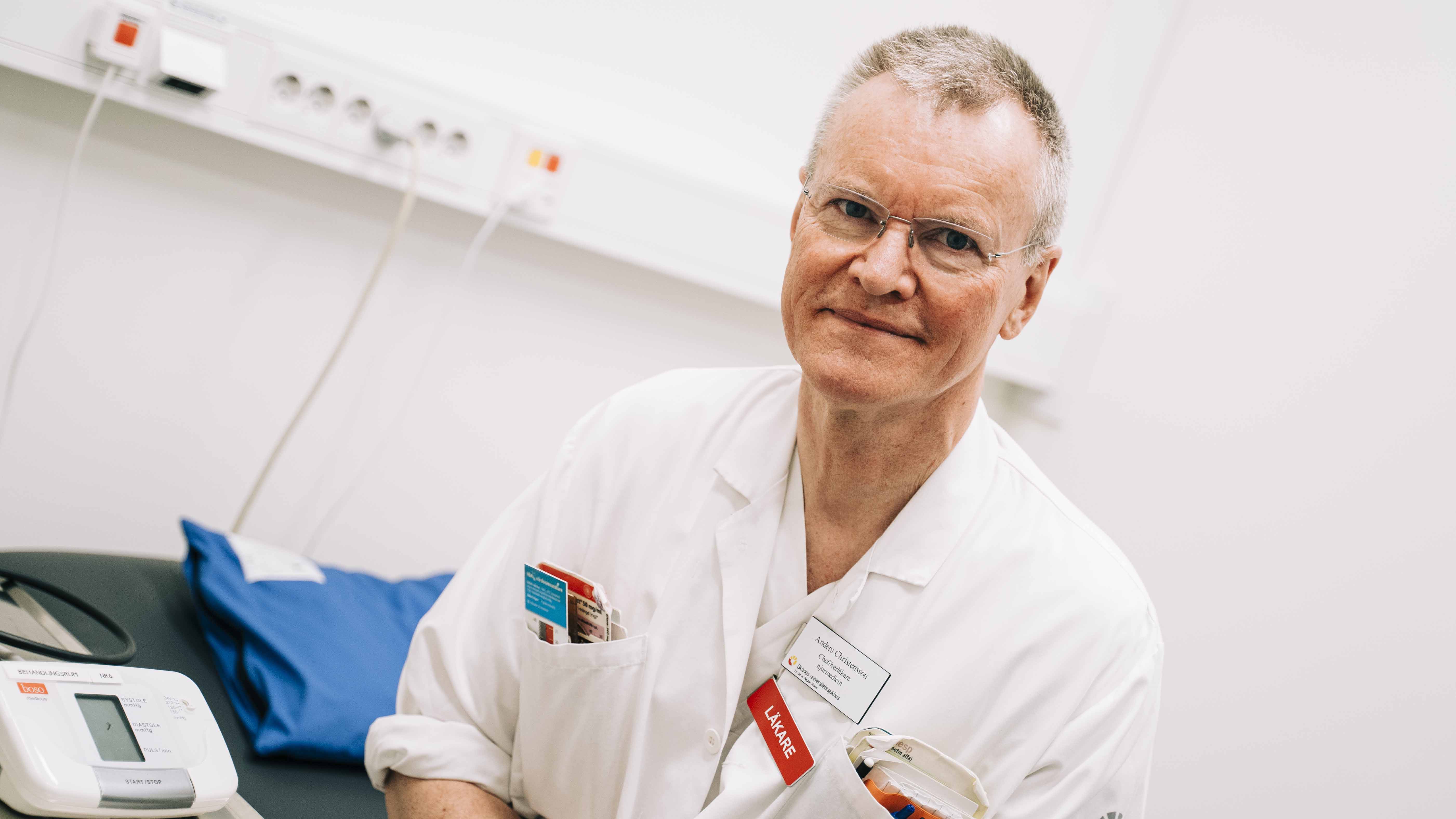 Läkaren Anders Christensson i vita vårdkläder i ett vårdrum.