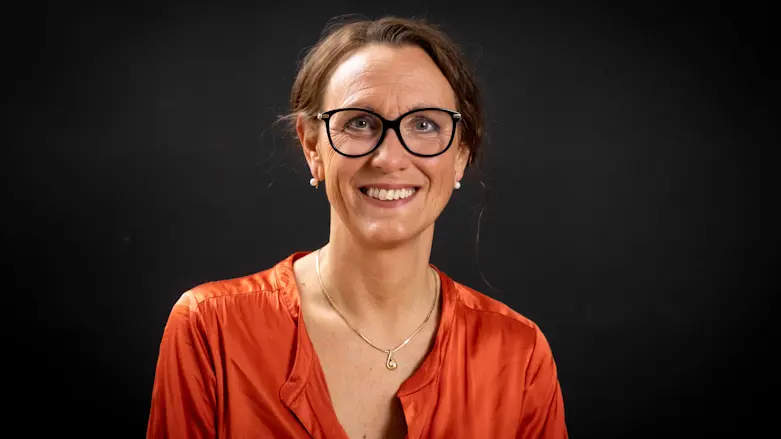 Annika Mellquist klädd i röd blus, fotad mot svart bakgrund.