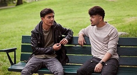 Två unga män som samtalar sittande på en bänk
