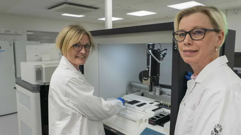 Sofia Gruvberger Saal, sektionschef vid Molekylär diagnostik och Maj Westman, erksamhetschef VO Klinisk genetik patologi och molekylär diagnostik, står i ett labb i vita labbrockar och tittar in i kameran.