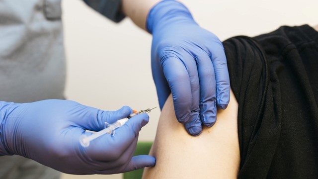 Uppkavlad ärm över en arm som vaccineras
