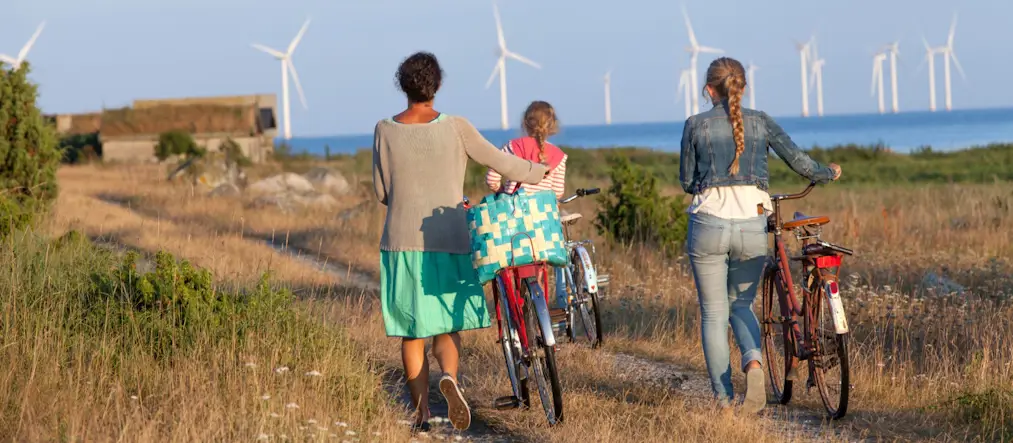 Vindkraftverk i bakgrunden, cyklister i framgrunden.