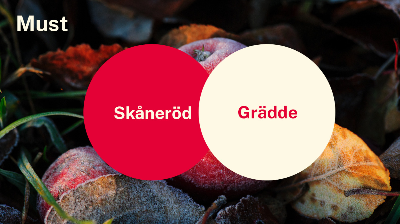 Färgerna Skåneröd och Grädde i två cirklar. I bakgrunden syns några röda äpplen med frost på, liggandes i gräs..